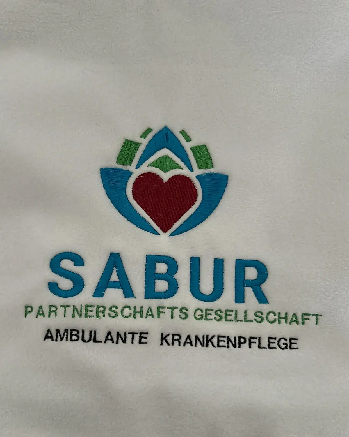 Weiße Fleecejacke mit mehrfarbiger Logostickerei für einen ambulanten Pflegedienst