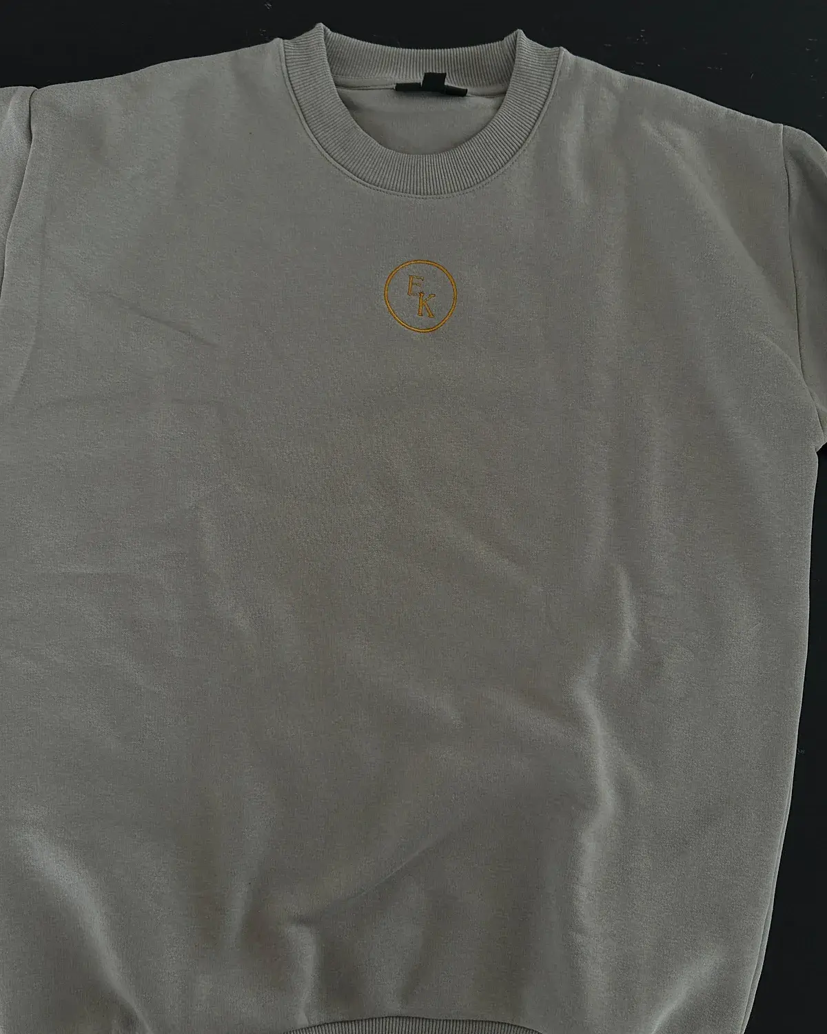 Sandgraues Sweatshirt mit dezenter Monogramm-Stickerei in Ocker auf der Brust