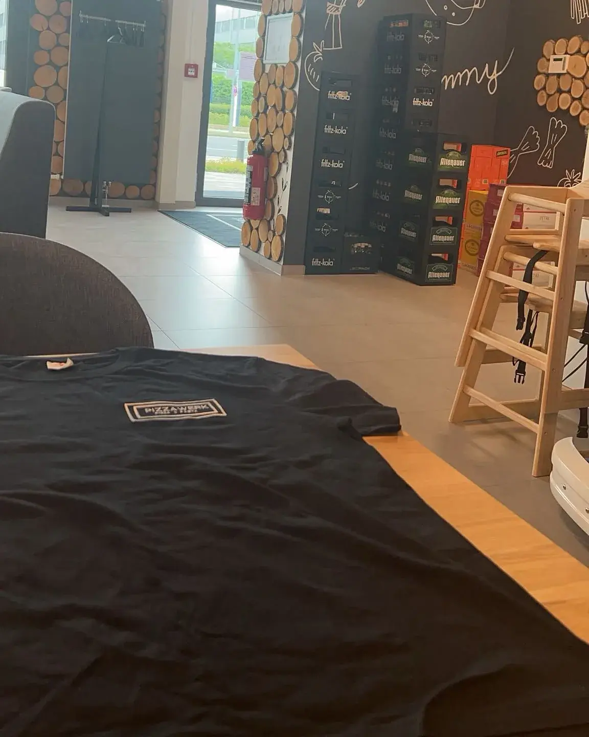 Schwarzes T-Shirt mit Bruststickerei vor Ort im Ladenlokal eines Gastronomiebetriebs