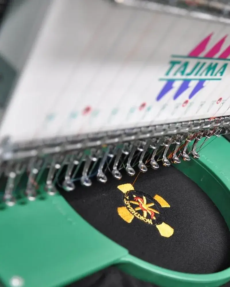Cap mit Stickerei im Rahmen der Stickmaschine in der Werkstatt in Peine