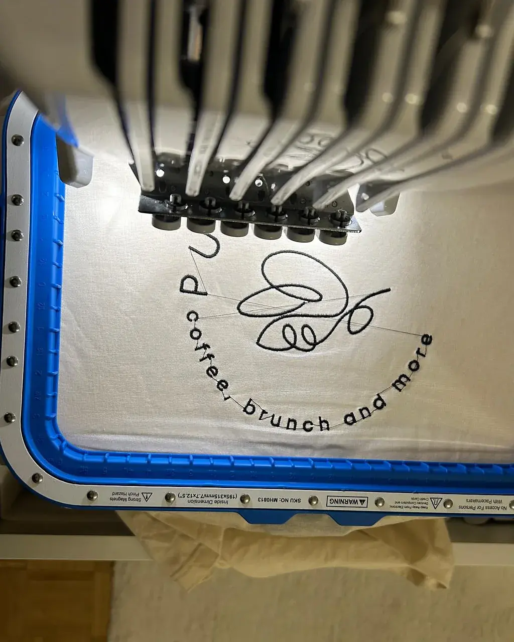 Shirt im Stickrahmen der Stickmaschine, Logostickerei in Arbeit in unserer Werkstatt in Peine